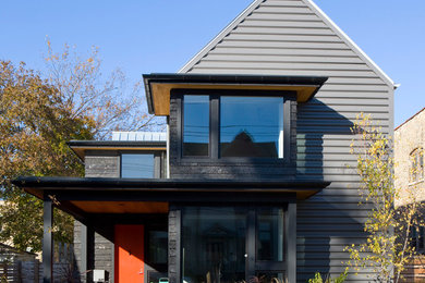 Modelo de fachada negra minimalista de tamaño medio de dos plantas con revestimientos combinados y tejado a dos aguas