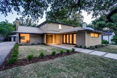Photo of a large and gey retro two floor brick house exterior in Dallas with a hip roof.