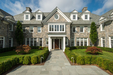 Photo of a classic house exterior in New York with three floors, stone cladding and a pitched roof.