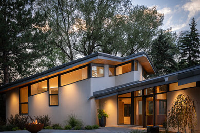 Inspiration for a mid-sized contemporary white two-story stucco house exterior remodel in Denver with a shed roof and a metal roof