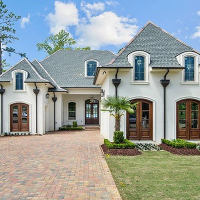Inspiration for a mid-sized timeless white one-story stucco house exterior remodel in New Orleans with a hip roof and a shingle roof