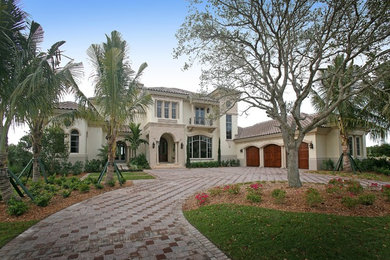 Example of a huge tuscan beige two-story stucco exterior home design in Miami with a hip roof