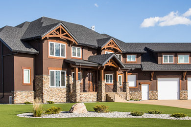 Large craftsman brown two-story stucco house exterior idea in Other with a hip roof and a shingle roof