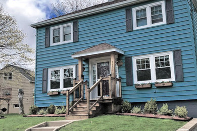 Modelo de fachada de casa pareada azul de dos plantas con revestimiento de madera