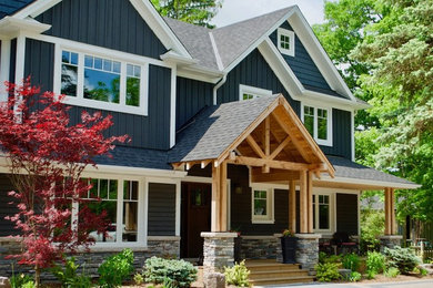 Diseño de fachada de casa azul de estilo americano de dos plantas con revestimientos combinados, tejado a dos aguas y tejado de teja de madera
