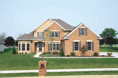Design ideas for a large and yellow classic two floor brick house exterior in Other with a half-hip roof.