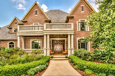 Huge elegant red two-story brick exterior home photo in Other