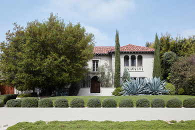 This is an example of a large and white mediterranean two floor render detached house in Los Angeles with a hip roof, a tiled roof and a red roof.