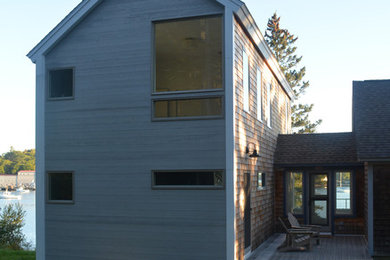 Modelo de fachada de casa gris actual de tamaño medio de dos plantas con revestimiento de madera y tejado a dos aguas