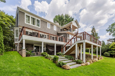 Modelo de fachada de casa gris de estilo americano grande de tres plantas con revestimiento de madera