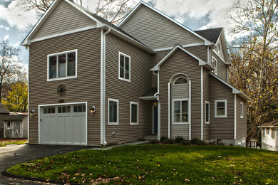 Cette photo montre une grande façade de maison beige chic à un étage avec un revêtement en vinyle et un toit à deux pans.