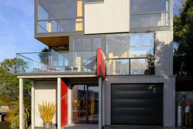 Foto de fachada de casa gris industrial pequeña de tres plantas con revestimiento de metal, tejado plano y tejado de metal