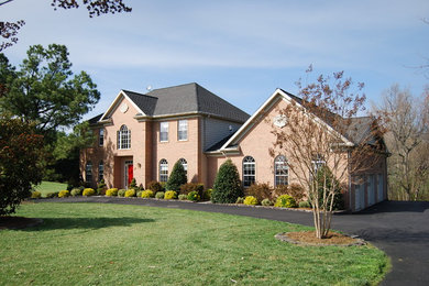 Large elegant red two-story brick house exterior photo in Baltimore with a hip roof and a shingle roof