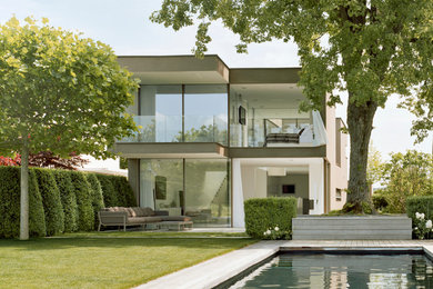Diseño de fachada de casa beige minimalista de tamaño medio de dos plantas con revestimiento de estuco y tejado plano