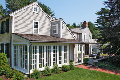 This is an example of a large and yellow traditional two floor detached house in Boston with wood cladding, a pitched roof and a shingle roof.