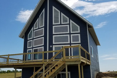 Imagen de fachada de casa azul marinera pequeña de dos plantas con revestimiento de madera y tejado a dos aguas