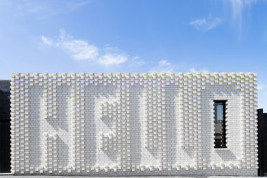 Foto della facciata di una casa piccola bianca contemporanea a un piano con rivestimento in mattoni e tetto piano