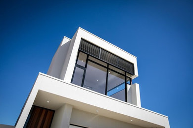Diseño de fachada de casa blanca actual de dos plantas con revestimiento de ladrillo, tejado plano y tejado de metal