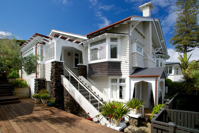Immagine della facciata di una casa grande beige classica a due piani con rivestimento in legno e tetto a capanna