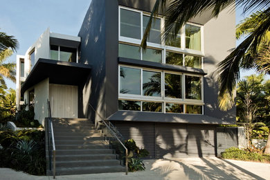 Example of a large minimalist gray two-story stucco exterior home design in Miami