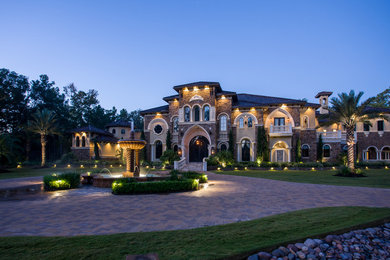 Example of a huge tuscan beige two-story stone exterior home design in Houston with a hip roof