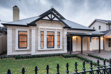 Modelo de fachada de casa beige clásica grande de una planta con revestimiento de piedra, tejado a dos aguas y tejado de metal