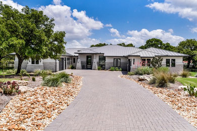 This is an example of an expansive and gey contemporary bungalow detached house in Austin with stone cladding, a hip roof and a metal roof.