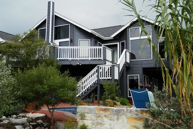 Imagen de fachada de casa gris ecléctica grande de dos plantas con revestimiento de madera y tejado de teja de madera