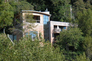 Ejemplo de fachada de casa marrón actual grande de tres plantas con revestimiento de madera, tejado plano y tejado de metal