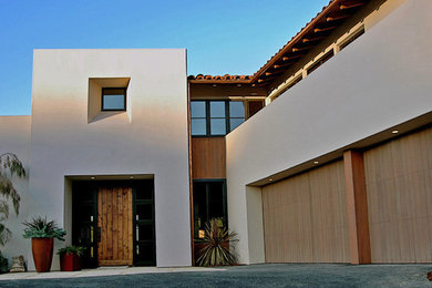 Exemple d'une grande façade de maison blanche éclectique en stuc à un étage avec un toit plat.