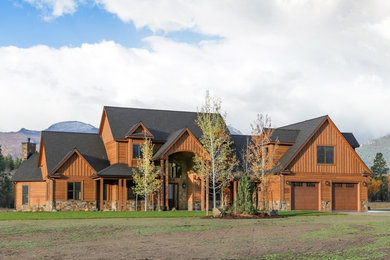 Réalisation d'une grande façade de maison marron chalet en bois à un étage avec un toit à deux pans et un toit en shingle.