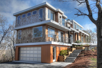 Aménagement d'une grande façade de maison marron bord de mer en bois à deux étages et plus avec un toit plat.
