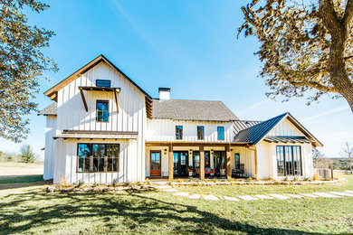 Immagine della villa ampia bianca country a due piani con rivestimento in legno, tetto a capanna e copertura mista