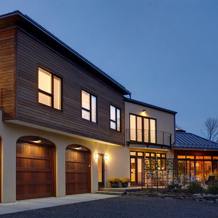 Esempio della villa grande beige contemporanea a due piani con rivestimento in legno, tetto a capanna e copertura in metallo o lamiera