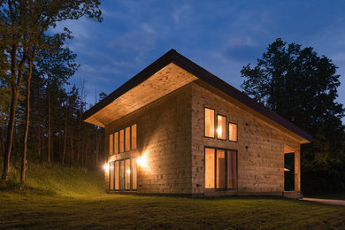 Cette photo montre une façade de maison montagne en bois de taille moyenne et à un étage avec un toit en appentis et un toit en métal.