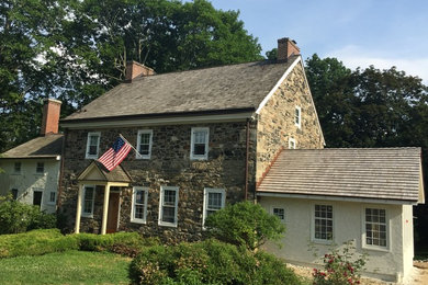 Large farmhouse beige three-story stone gable roof photo in Philadelphia