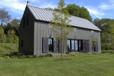 Aménagement d'une petite façade de maison grise campagne en panneau de béton fibré à un étage avec un toit à deux pans et un toit en métal.