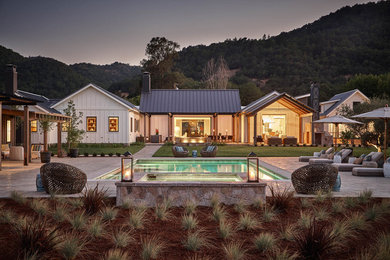 Imagen de fachada de casa blanca de estilo de casa de campo de una planta con tejado a dos aguas y tejado de metal