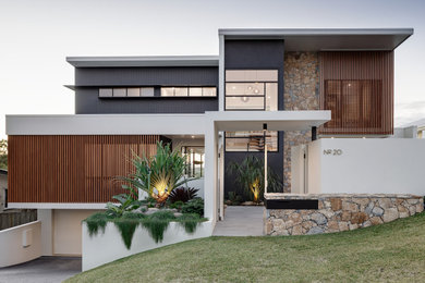 Modelo de fachada de casa multicolor y blanca contemporánea grande de tres plantas con revestimiento de piedra y tejado plano
