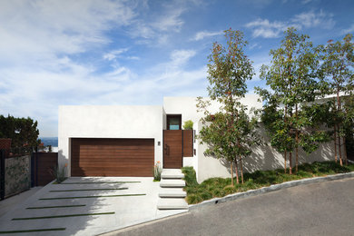 Diseño de fachada de casa blanca actual de tamaño medio de tres plantas con tejado plano y revestimiento de estuco