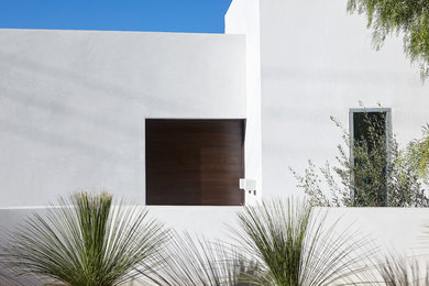 Modelo de fachada de casa blanca moderna de tamaño medio de dos plantas con revestimiento de estuco y tejado plano