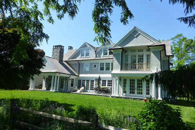 На фото: трехэтажный, деревянный, серый частный загородный дом среднего размера в классическом стиле с двускатной крышей и крышей из гибкой черепицы с
