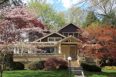 Ejemplo de fachada de casa gris de estilo americano de dos plantas con revestimiento de madera y tejado a dos aguas