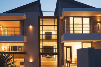 Diseño de fachada de casa beige moderna grande de dos plantas con revestimiento de estuco y tejado de un solo tendido