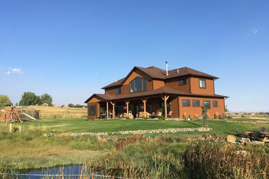 Imagen de fachada de casa marrón rústica grande de dos plantas con revestimiento de madera, tejado a dos aguas y tejado de teja de madera