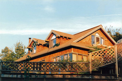 Diseño de fachada de casa beige costera de tamaño medio de dos plantas con revestimiento de madera, tejado a dos aguas y tejado de teja de madera