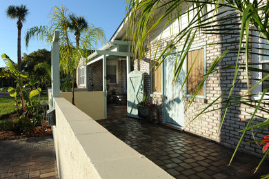 Imagen de fachada de casa beige costera de tamaño medio de dos plantas con revestimiento de ladrillo y tejado de teja de madera