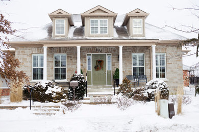 Mid-sized arts and crafts beige two-story stone house exterior photo in Toronto with a hip roof and a shingle roof
