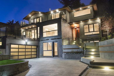 Large modern gray three-story stone exterior home idea in Vancouver