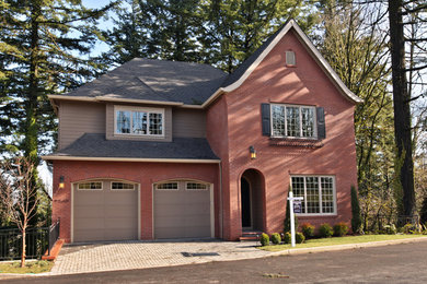 Example of a large red two-story brick exterior home design in Portland